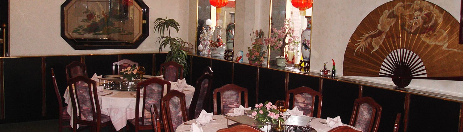 Een zaal van Sozing met ronde tafels, lampionnen en een geschilderde waaier aan de wand.